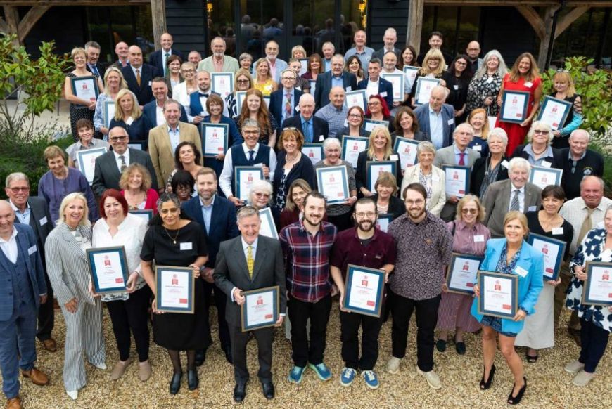 people standing and smiling at a camera, some holding award certificates